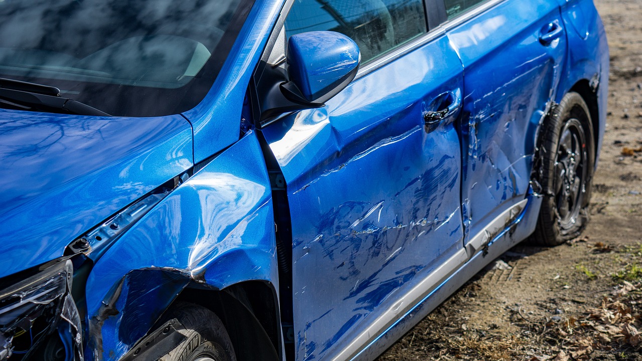 severely damaged blue car on dirt road