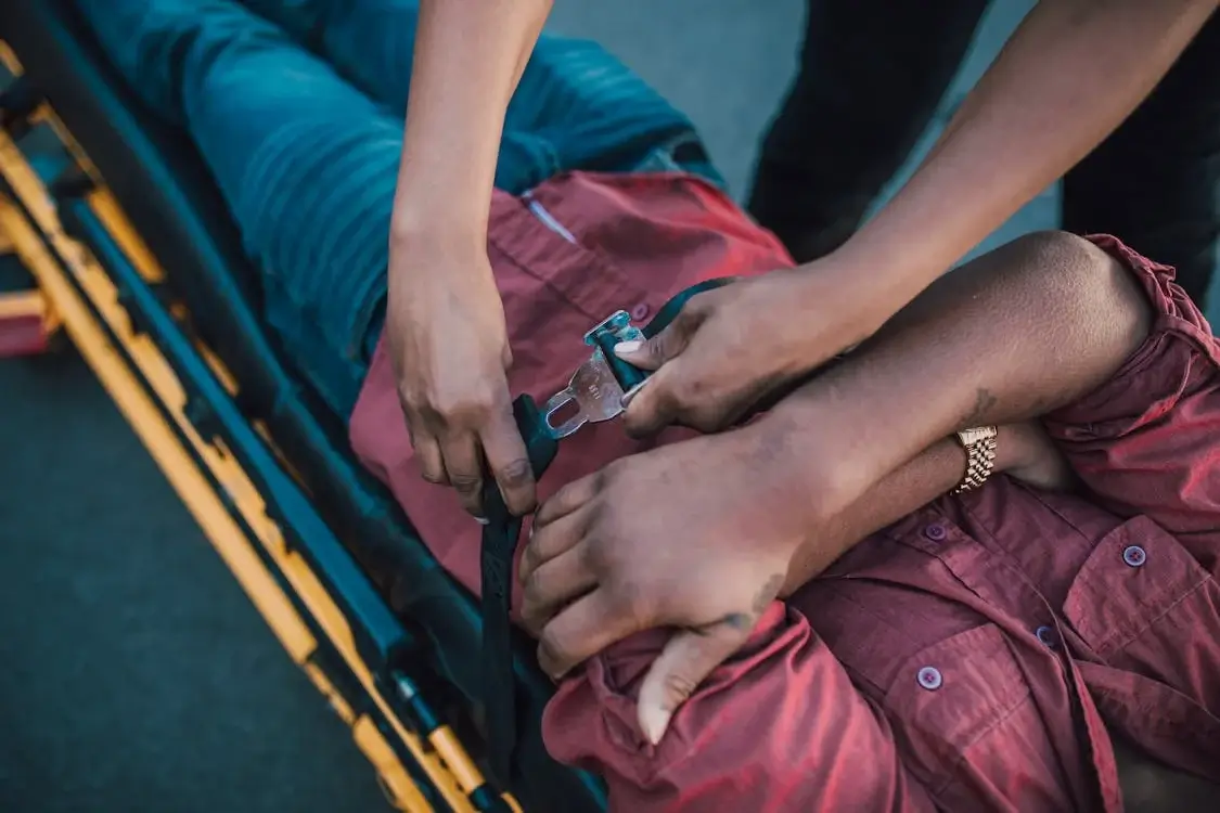 injured person getting buckled into stretcher by paramedic injured person getting buckled into stretcher by paramedic