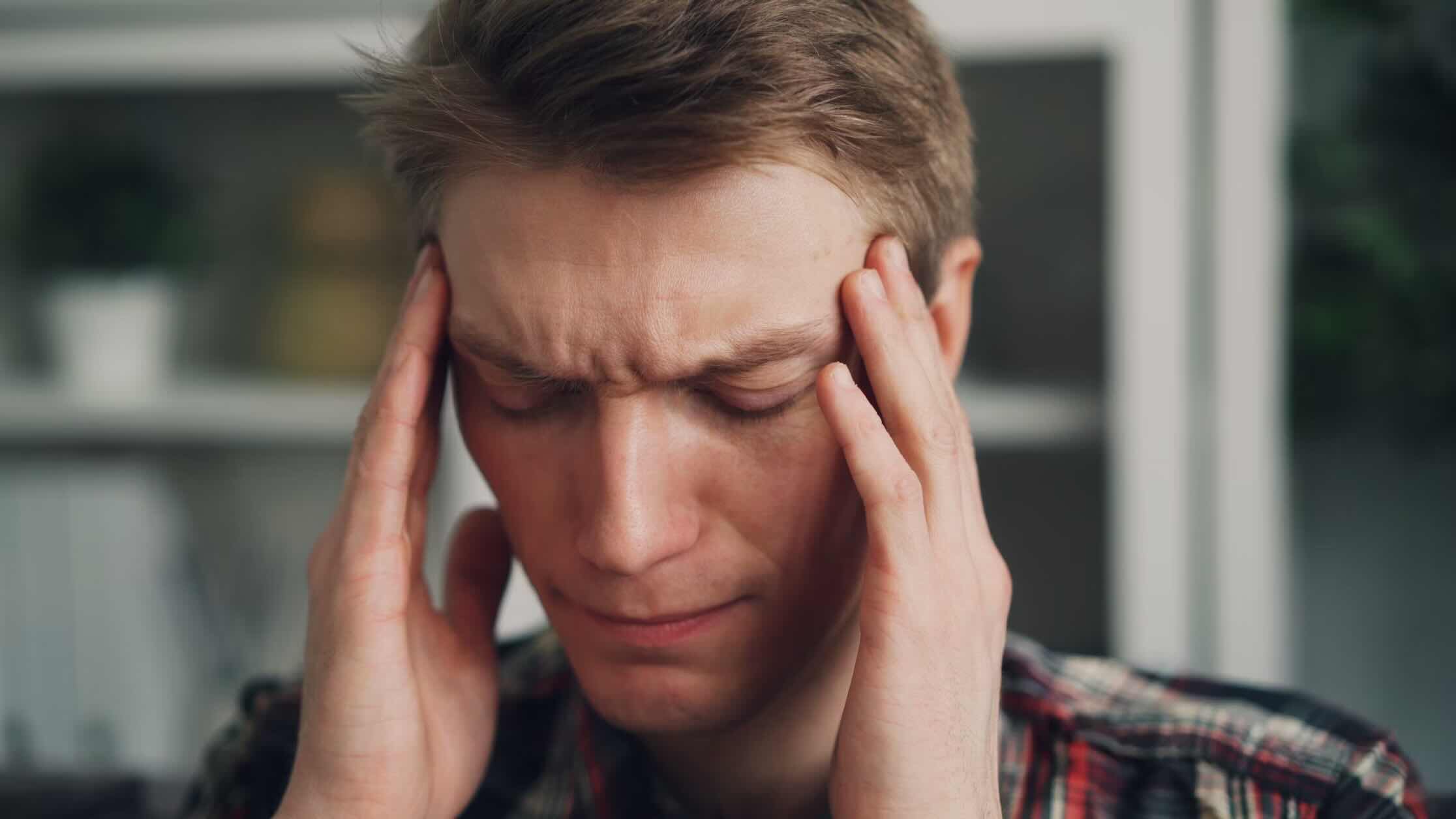 man coping with headache, holding hands to head